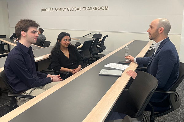 two students practice their interviewing skills with a professional in the classroom