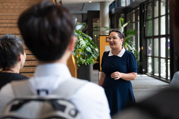 professional female smiles while speaking to students on a tour
