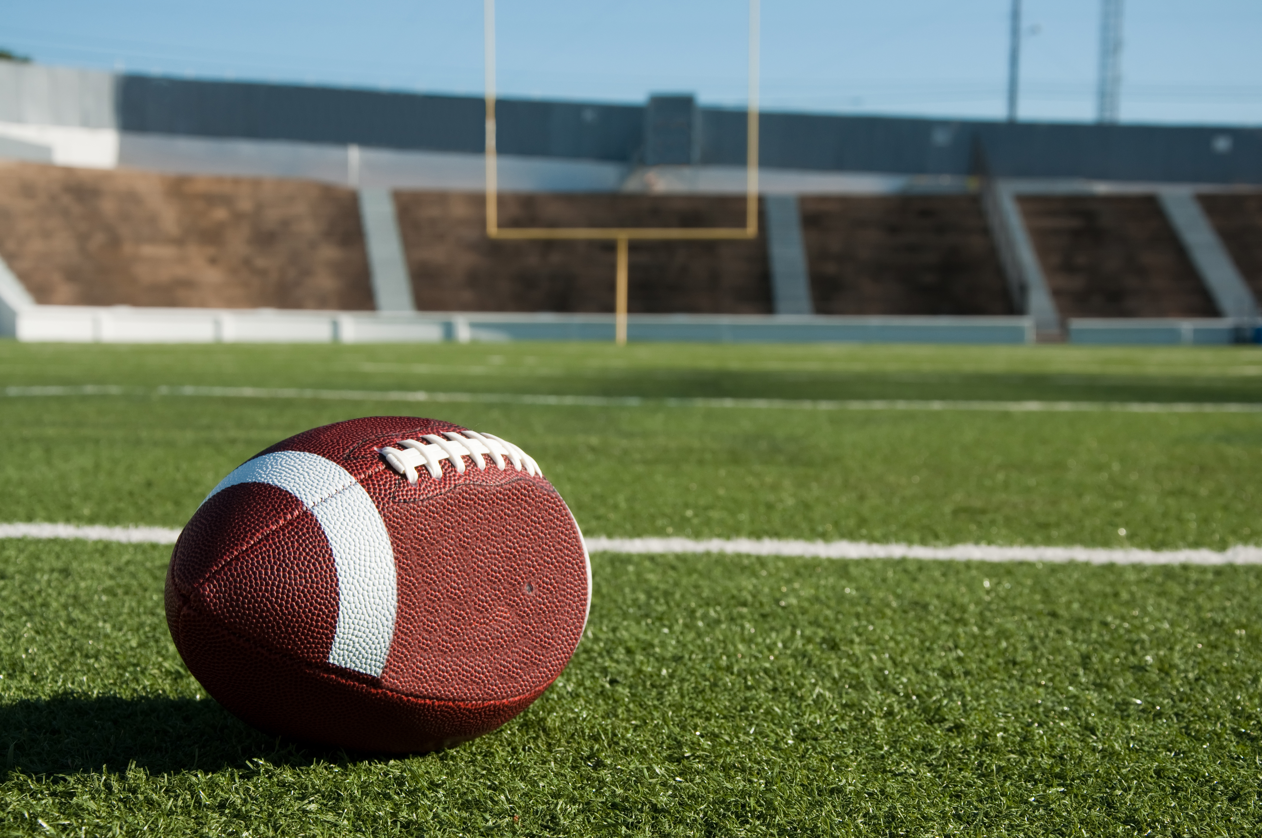 A football sits on a field in a football stadium. 