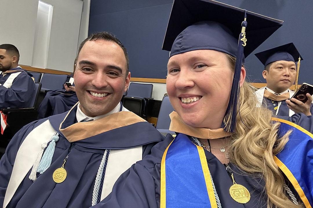 Guadalupe Vega, M.S. ‘23, a U.S. Army veteran, and Rebecca Strang, M.S. '23, a military spouse, both graduates of the Master of Human Resource Management (MHRM) program at the GW School of Business., posing for a selfie during graduation.  