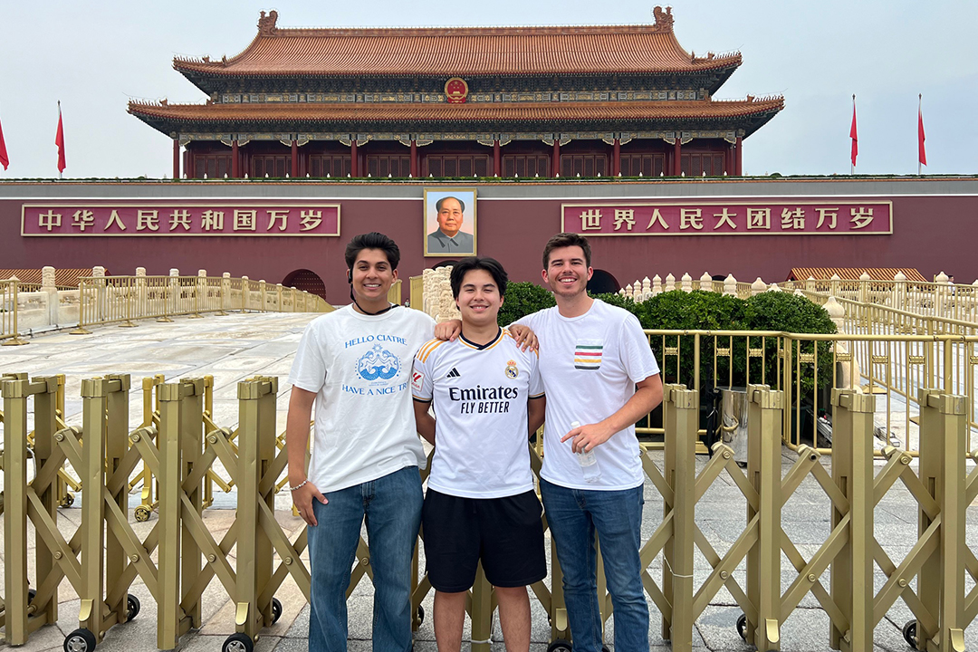 Three smiling GW students pose for a photo in front of a historical landmark building in China.