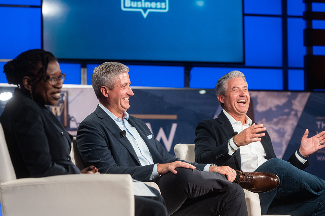Three people sitting on stage on george talks business smiling and laughing