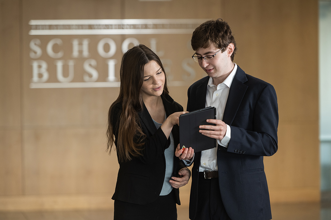 two GWSB students examine data on a tablet in Duques Hall