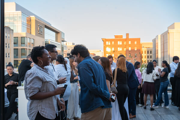 attendees laugh in conversation at a networking event on a rooftop