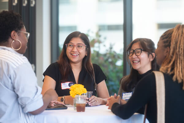 group of 4 students talk around small table at networking event