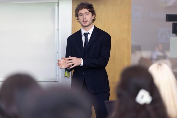 Student stands at front of classroom delivering presentation