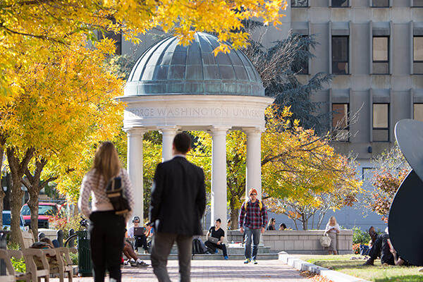 students walk toward Tempietto in Kogan Plaza, bright yellow fall leaves overhead