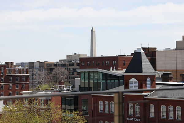 Washington Monument in the distance towers above GW campus buildings in the foreground