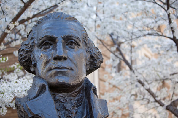 bust of George Washington, white blossoms on trees in the background
