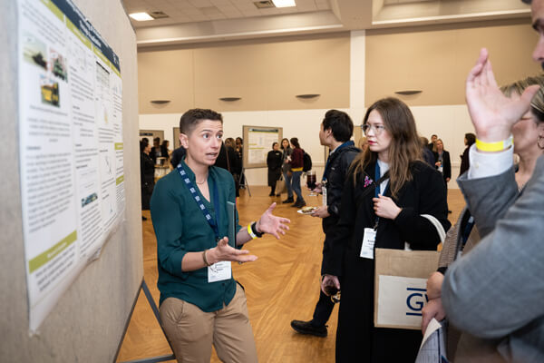 student explains their research on the research poster as audience members listen