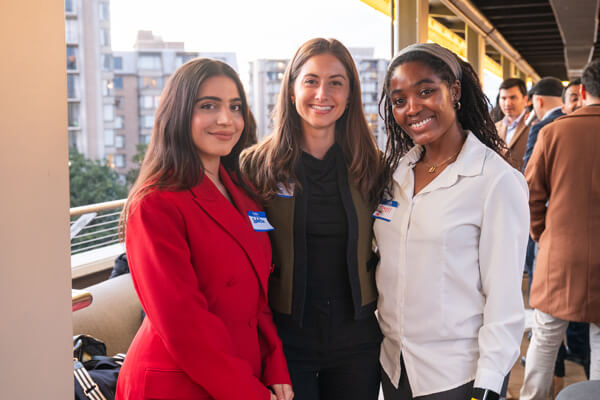 three students pose for a group photo at a networking event