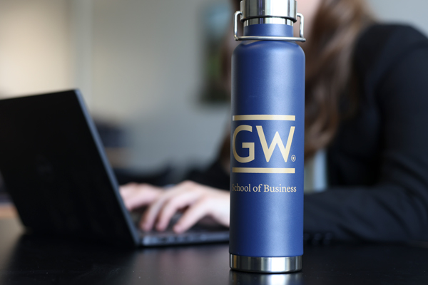 close up of GW metal water bottle, person types on laptop in background