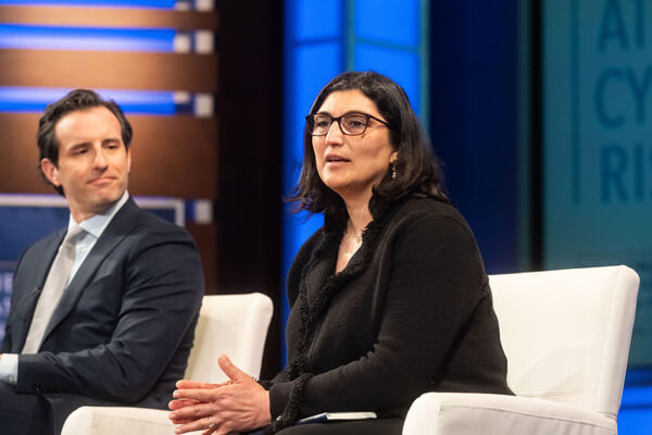 panelist at GW Business event seated on stage speaking, other panelist watches her from the side
