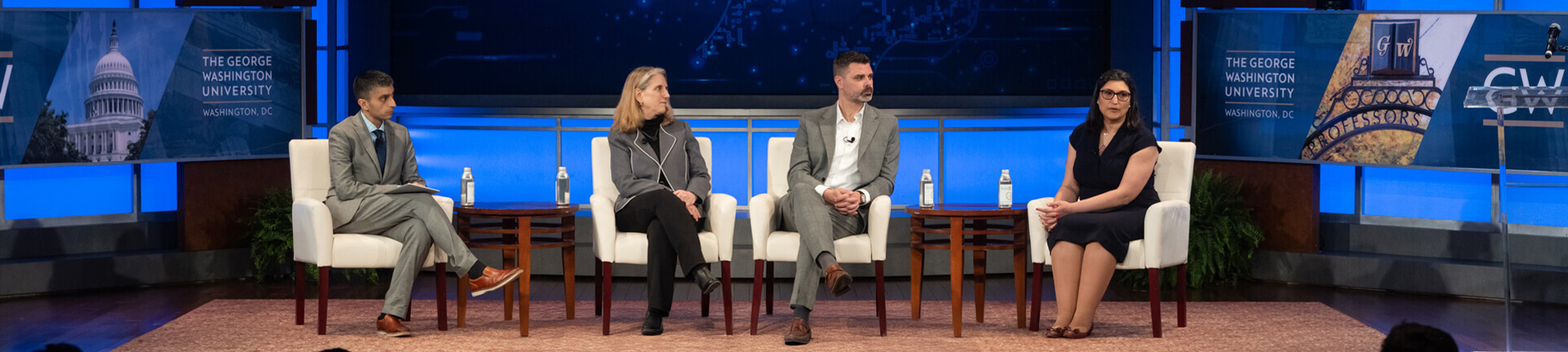 four panelists sit in white chairs on stage at the Business & Policy Forum