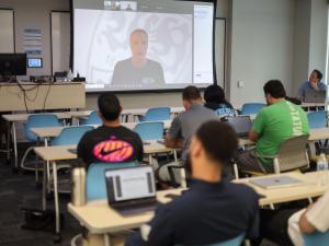 Scott Rezendes Zooms into a classroom full of students who watch him on the projector