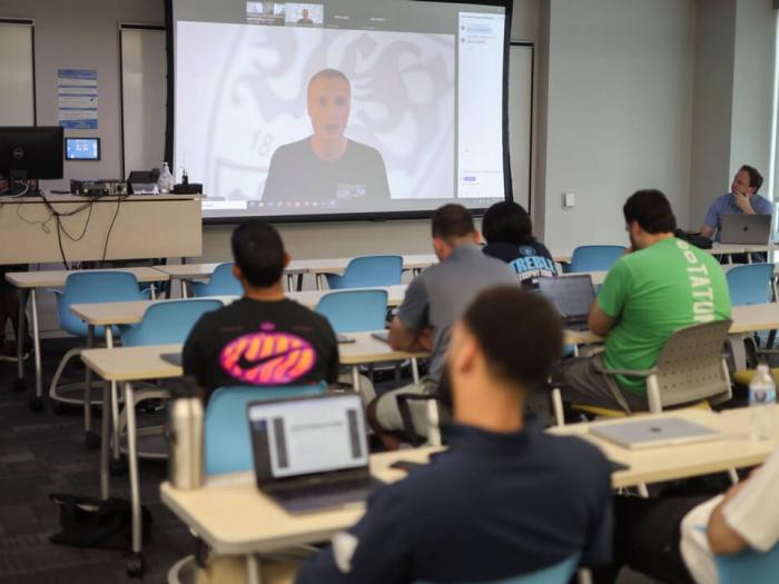 Scott Rezendes Zooms into a classroom full of students who watch him on the projector