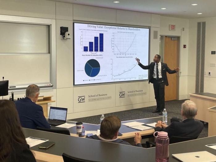 person presenting in front of projector with graphs on it