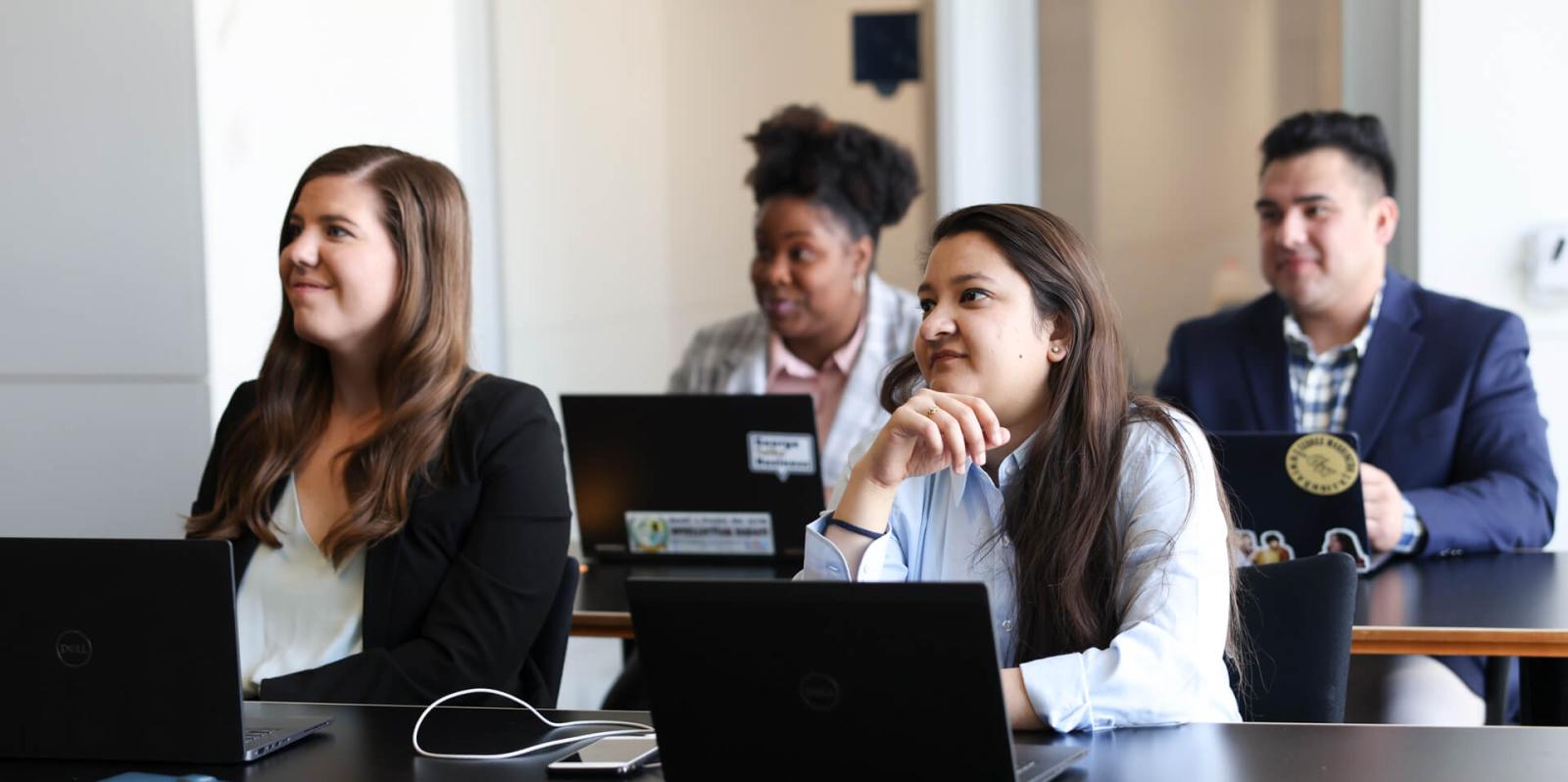 GW Business students listen to professor in classroom with laptops open in front of them