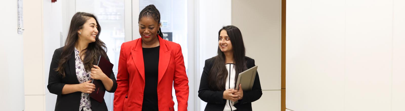 three GW Business students walk through the hall