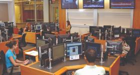 Students work on computers in the Capital Markets Trading Room in Duquès Hall. TV monitors also display news.
