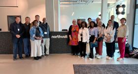 A group of people in a large office lobby in front of a desk with the text "Northvolt." 