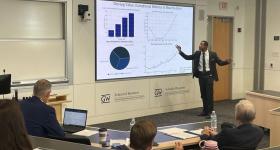person presenting in front of projector with graphs on it