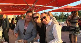 Matt Cohen, Carrie Potter and Mitch Blaser pose for a group photo under red outdoor umbrellas